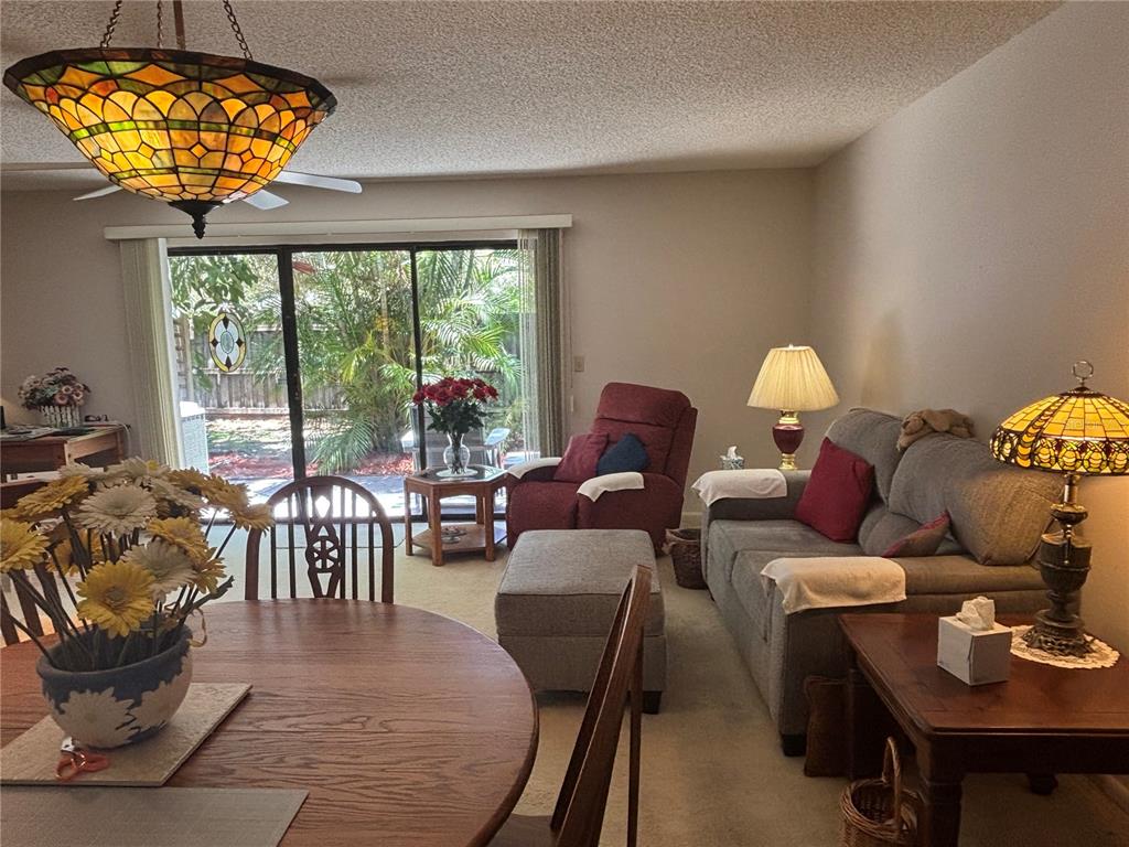 A dining area and living room feature a stained glass chandelier, carpet, and sliding doors — 1515 BAYSHORE BOULEVARD UNIT 26, DUNEDIN, FL