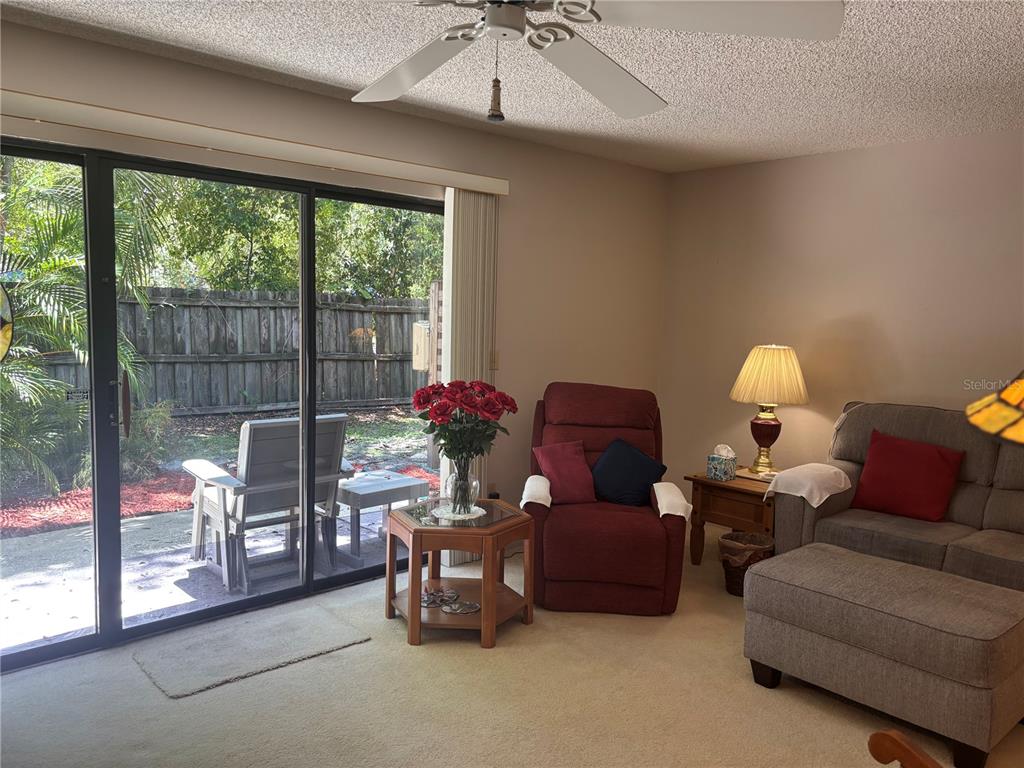 A living room features a sliding glass door, a red recliner, and a gray sofa — 1515 BAYSHORE BOULEVARD UNIT 26, DUNEDIN, FL