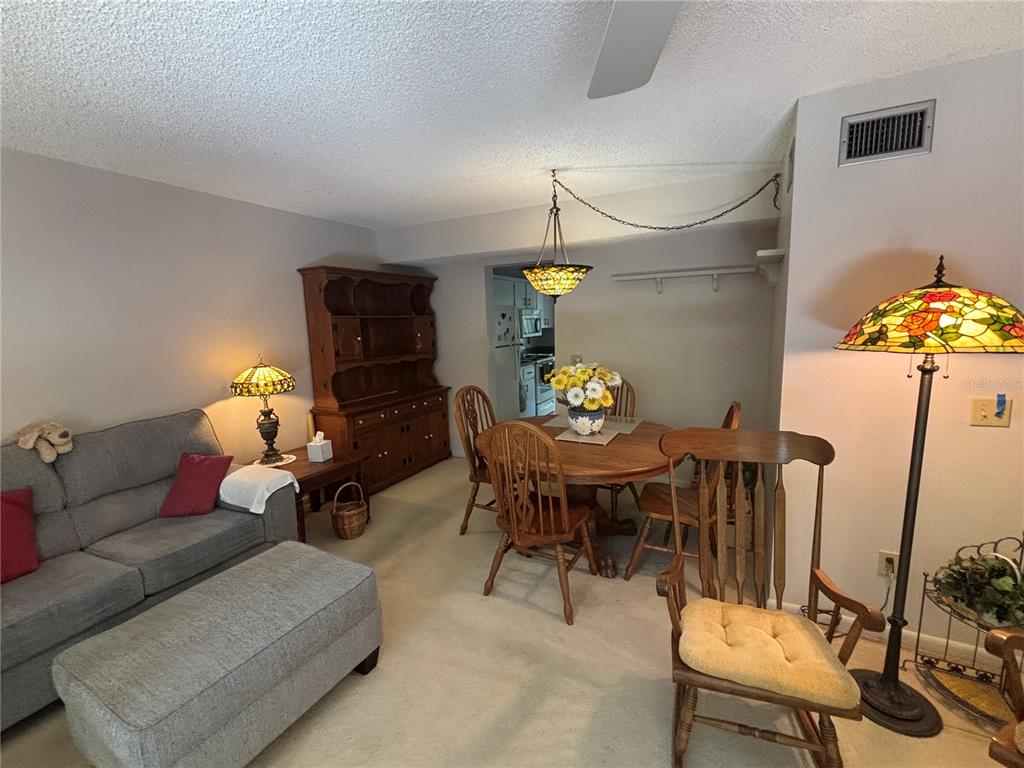 A living and dining area features a grey sofa, wooden hutch, and a round dining table — 1515 BAYSHORE BOULEVARD UNIT 26, DUNEDIN, FL