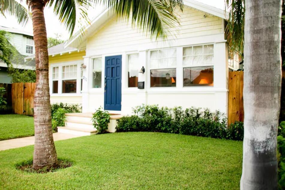 A yellow bungalow with a blue front door, white trim, and a manicured front lawn — 211 N Ocean Breeze # 1, FL 33460, FL