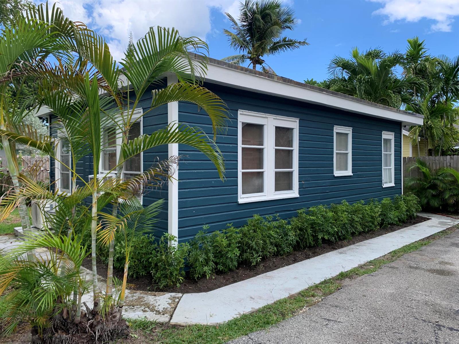 A blue exterior house with white trim, a concrete walkway, and surrounding palm trees — 211 N Ocean Breeze # 1, FL 33460, FL