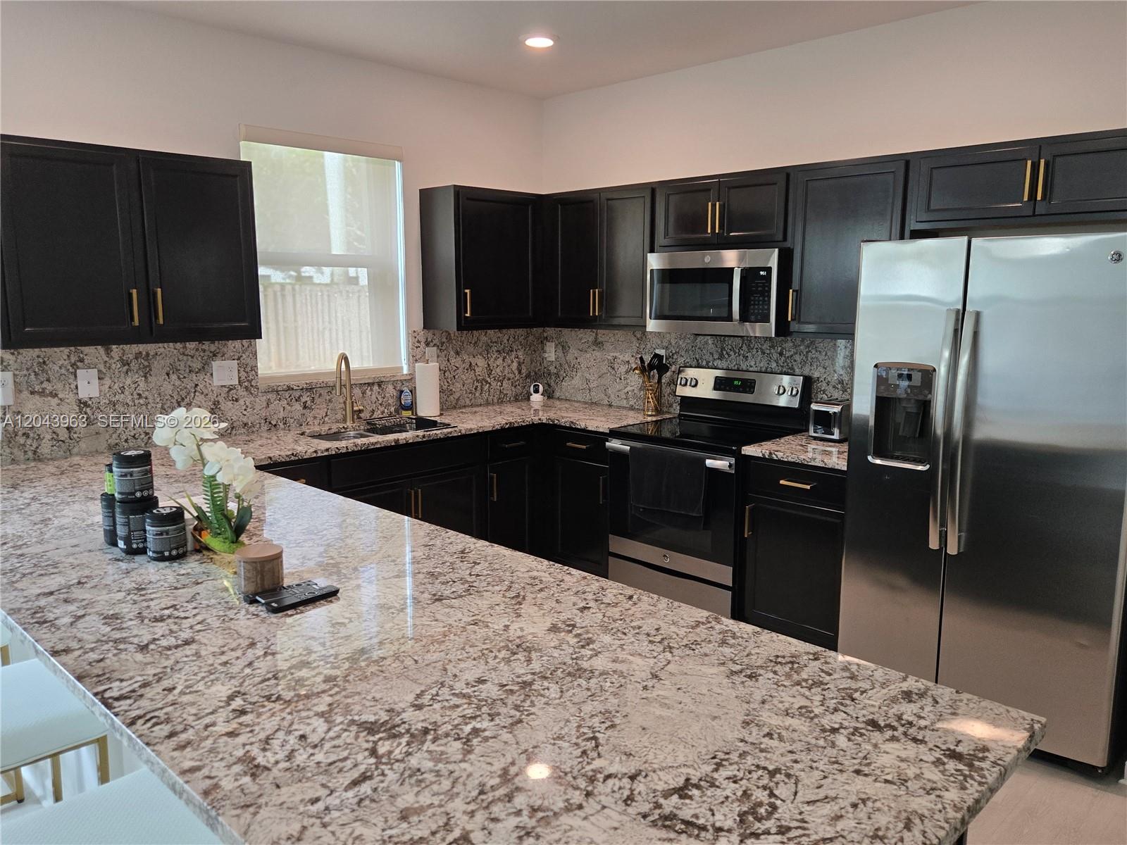 A kitchen features dark cabinets, granite countertops, stainless steel appliances, and a large island — 634 SE 37 Ave, Homestead FL 33033, HOMESTEAD, FL