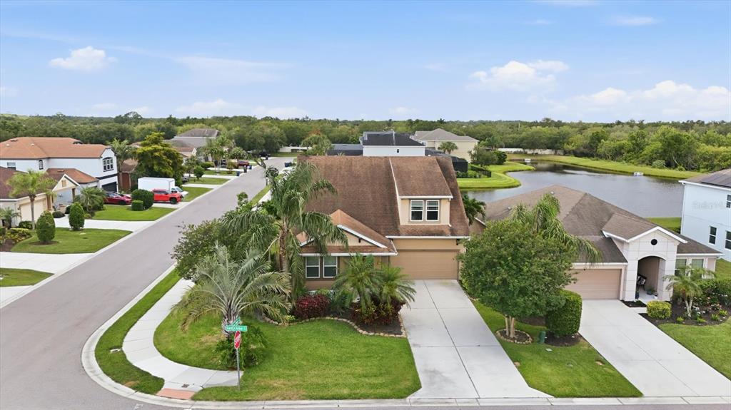 An aerial view shows a suburban neighborhood with houses, a pond, and green landscaping — 4718 GARDEN ARBOR WAY, BRADENTON, FL