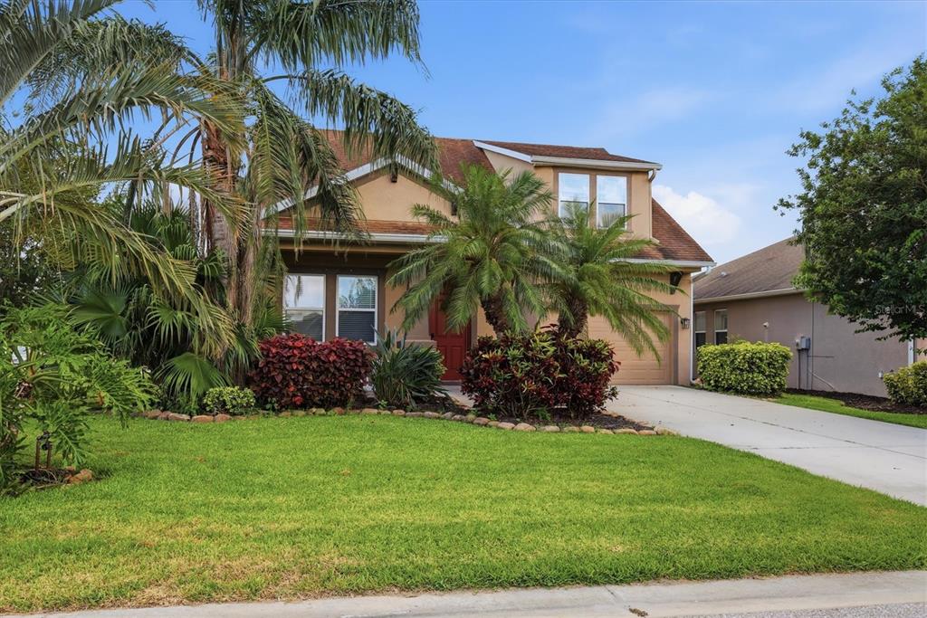 A two-story suburban house with a tan exterior, a palm tree, and a concrete driveway — 4718 GARDEN ARBOR WAY, BRADENTON, FL