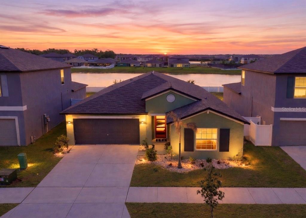 An aerial view of a single-story house with a garage at sunset by a lake — 13327 GREAT PLAINS DRIVE, RIVERVIEW, FL