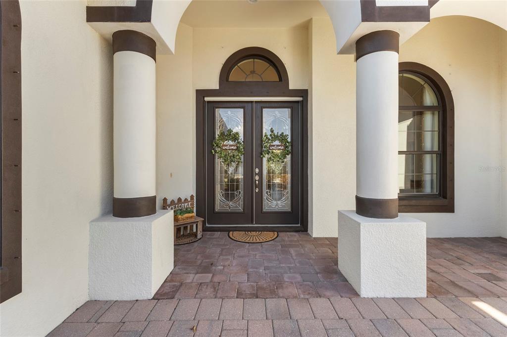 A covered entryway features double glass doors, two large columns, and a paved floor — 576 MAST DRIVE, BRADENTON, FL