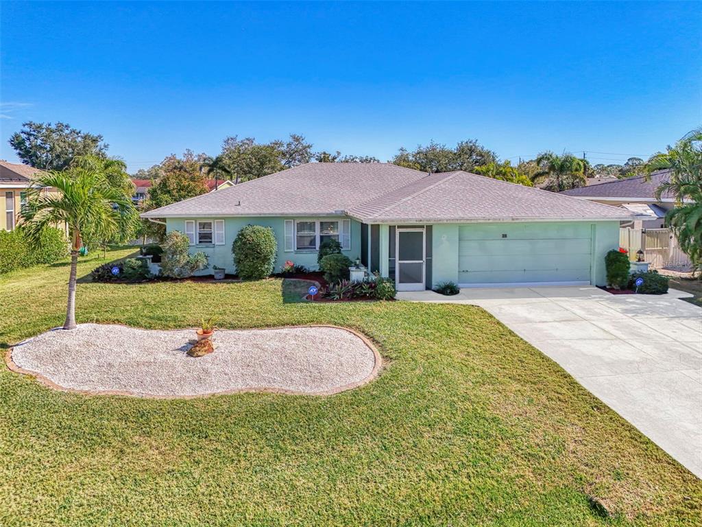 A light green, single-story ranch-style house features a two-car garage and a landscaped front yard — 602 PORTIA STREET N, NOKOMIS, FL