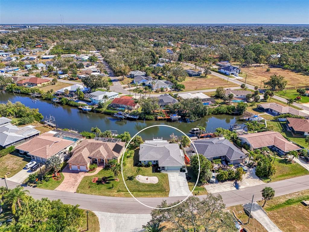 An aerial view shows a waterfront house with a concrete driveway and a boat dock — 602 PORTIA STREET N, NOKOMIS, FL