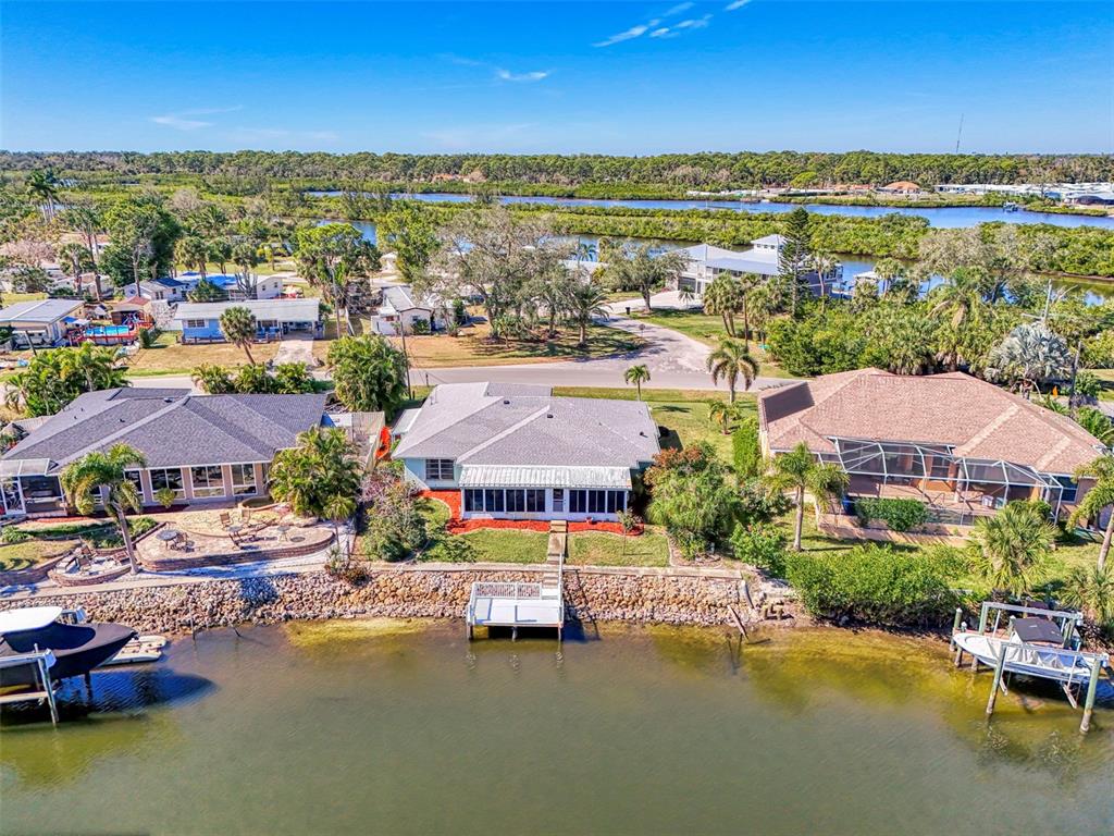 An aerial view shows three waterfront houses with docks along a canal — 602 PORTIA STREET N, NOKOMIS, FL