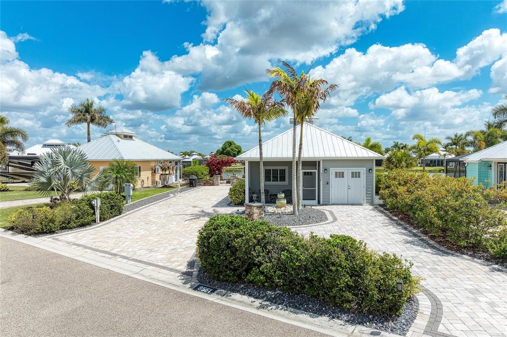 A gray cottage with a metal roof and paver driveway sits under a blue sky — 8551 SW SAND CRANE CIRCLE LOT 55, ARCADIA, FL