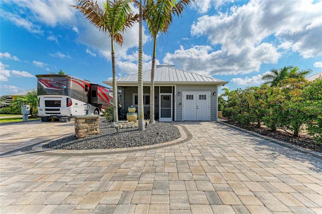 A paved driveway leads to a house with a metal roof and an adjacent RV — 8551 SW SAND CRANE CIRCLE LOT 55, ARCADIA, FL