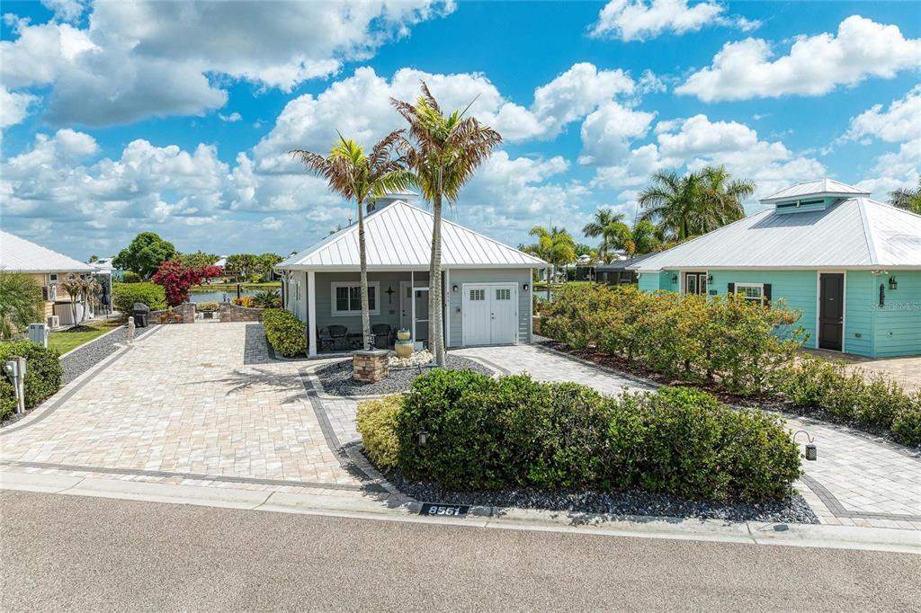 A gray cottage with a metal roof and paver driveway sits under a blue sky — 8551 SW SAND CRANE CIRCLE LOT 55, ARCADIA, FL