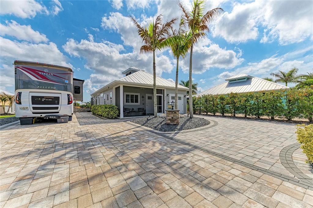 A Tiffin Allegro motorhome is parked on a paved driveway next to a coastal-style house — 8551 SW SAND CRANE CIRCLE LOT 55, ARCADIA, FL