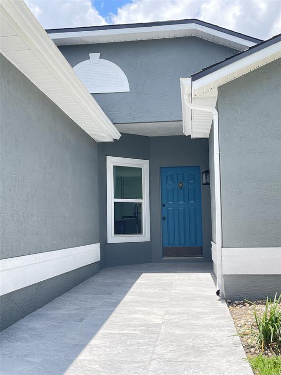 A gray house exterior features a blue front door, a window, and tiled walkway — 2869 FALLING TREE CIRCLE, ORLANDO, FL