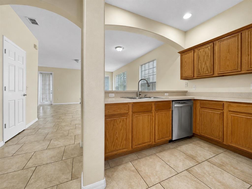 A kitchen with wood cabinets, a stainless steel dishwasher, and tile flooring — 1602 TAIL FEATHER DRIVE, KISSIMMEE, FL