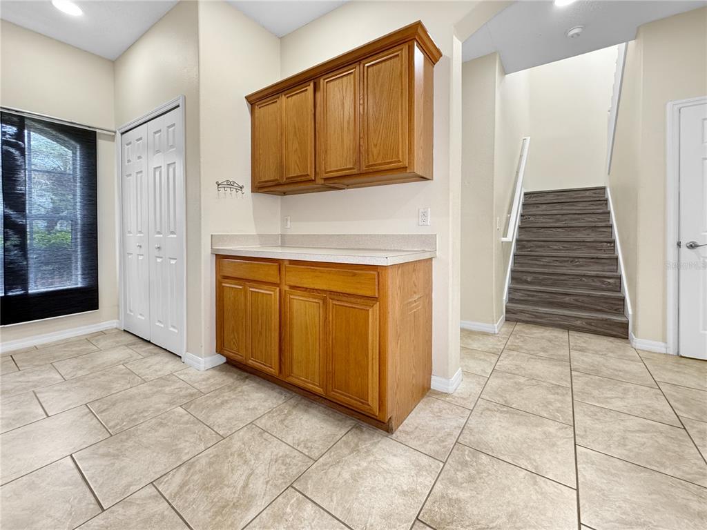 A room with tile flooring, wooden cabinets, a countertop, and a staircase — 1602 TAIL FEATHER DRIVE, KISSIMMEE, FL