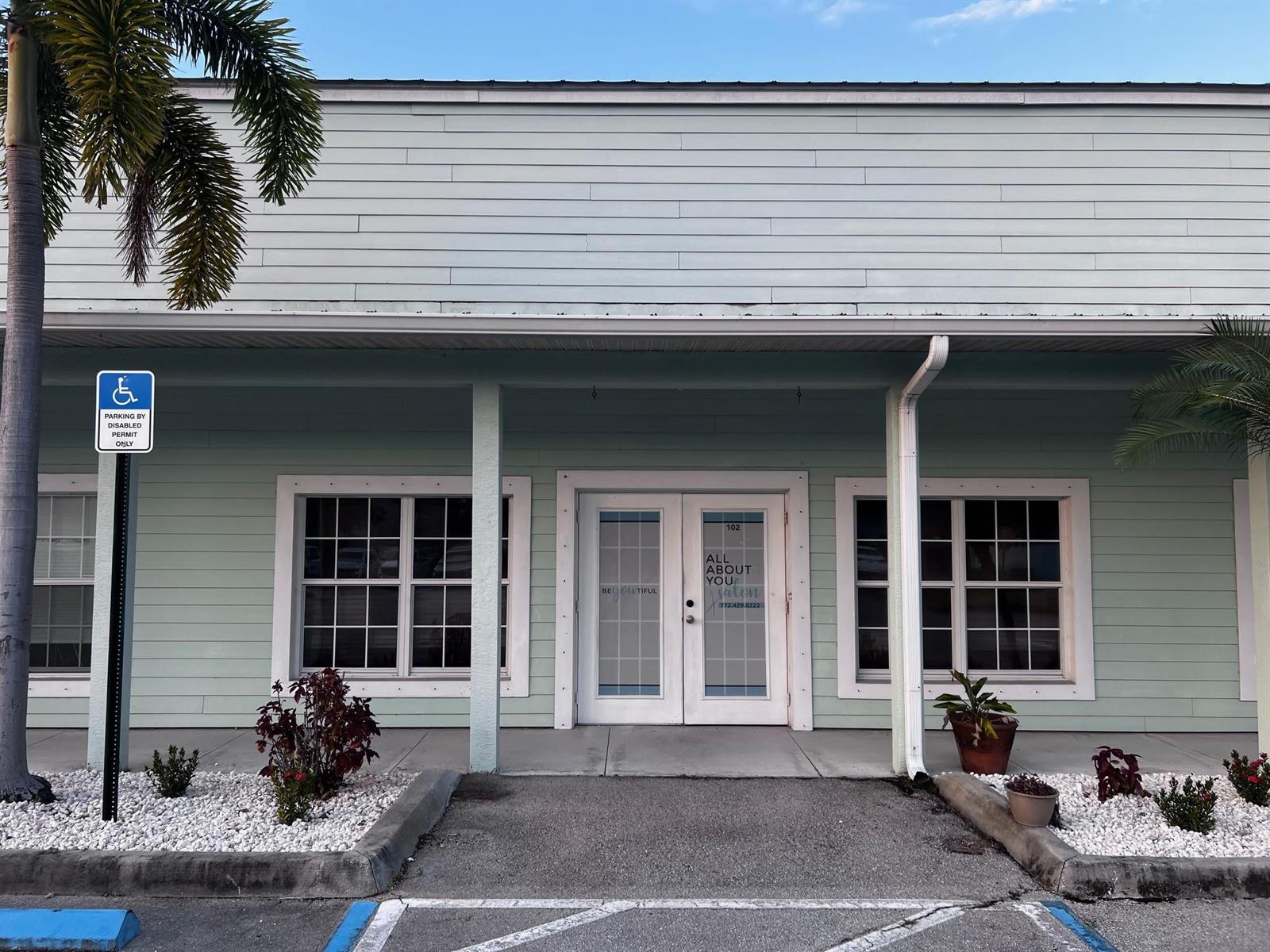 The exterior of a light green commercial building features a central double-door entrance and windows — 3731 Oleander # 102, Fort Pierce FL 34982, FORT PIERCE, FL