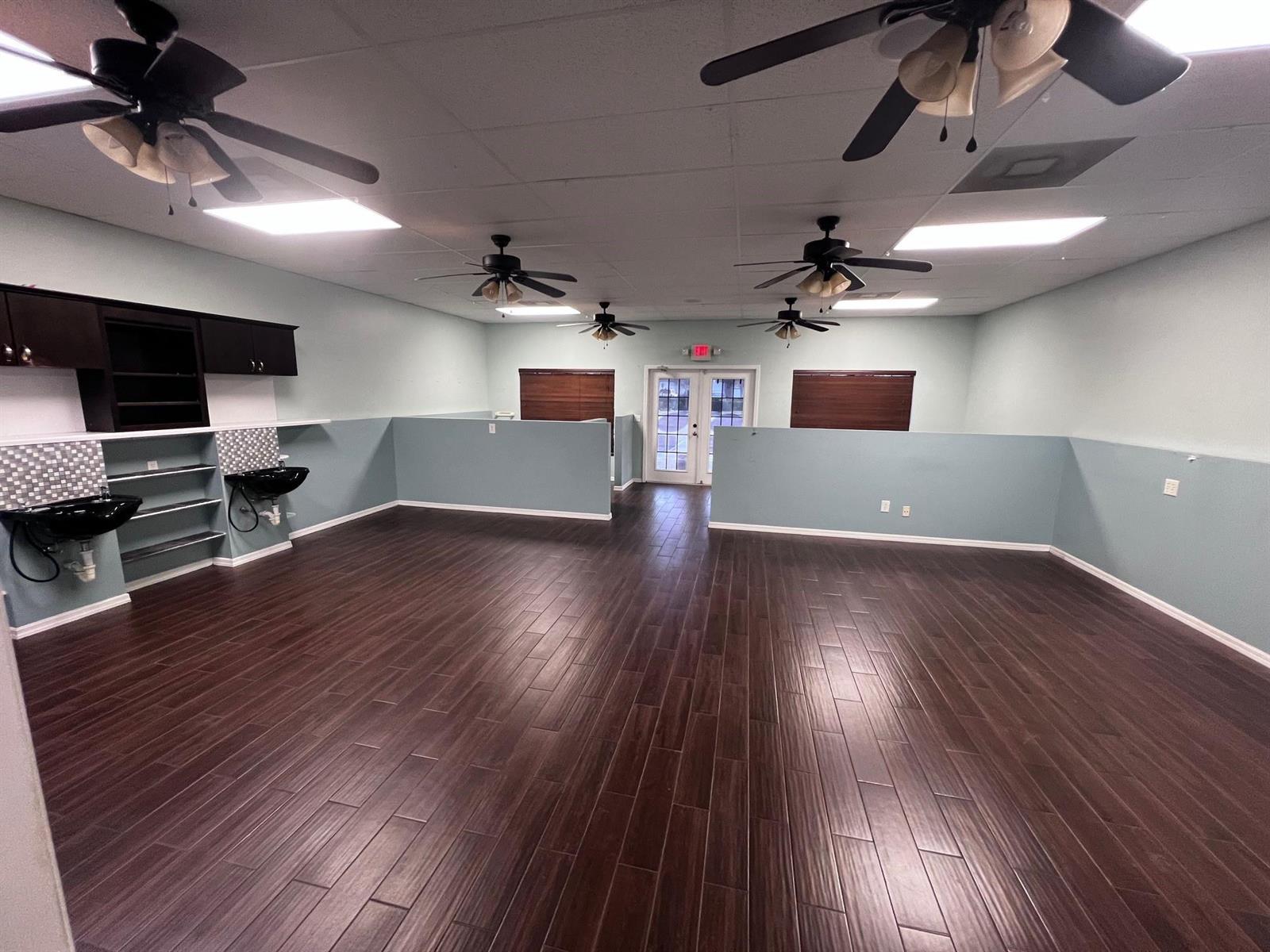 A spacious room features dark wood-look flooring, light blue walls, ceiling fans, and two sinks — 3731 Oleander # 102, Fort Pierce FL 34982, FORT PIERCE, FL