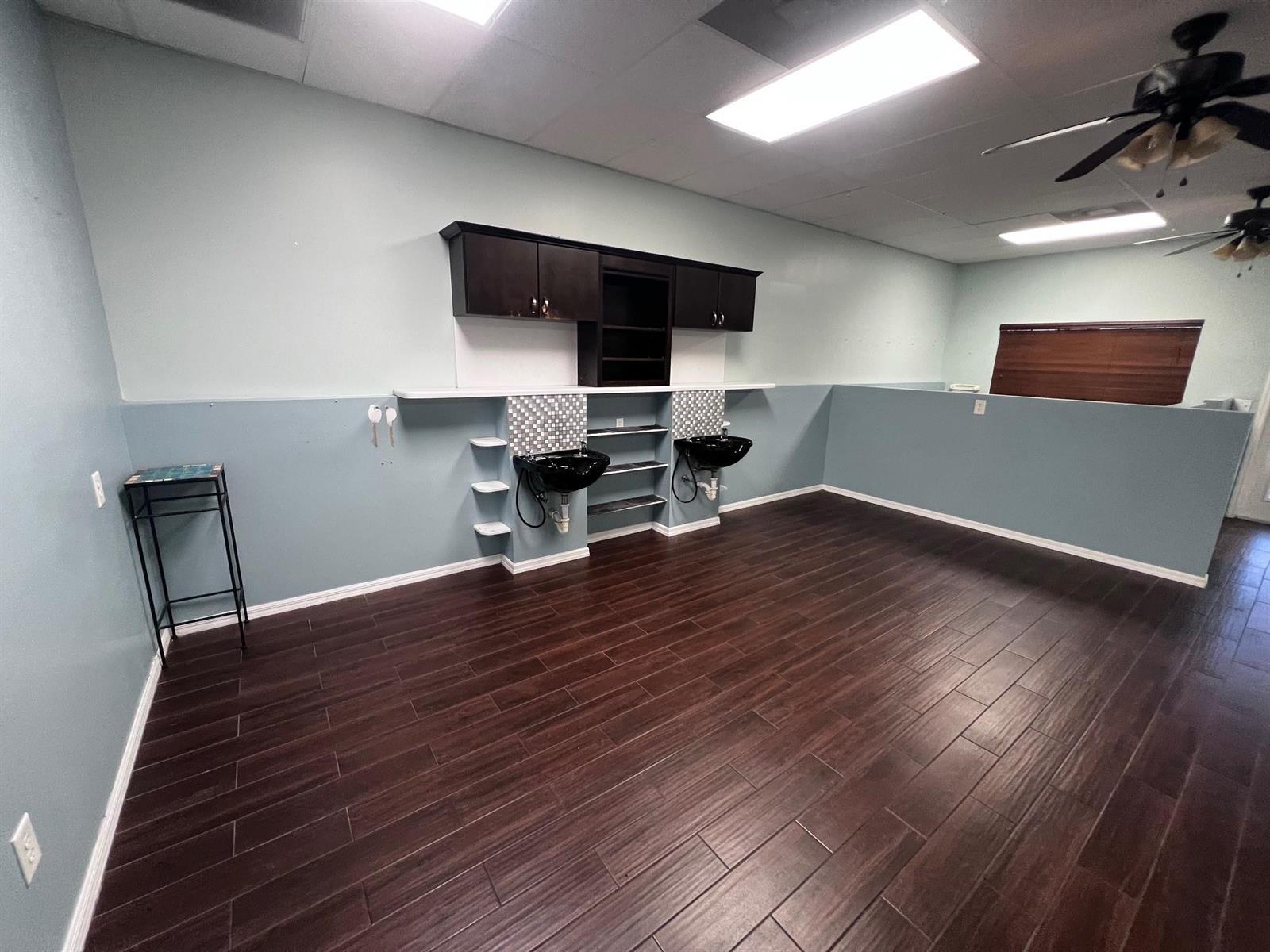 A salon room features two black shampoo sinks, dark cabinetry, and dark wood-look flooring — 3731 Oleander # 102, Fort Pierce FL 34982, FORT PIERCE, FL