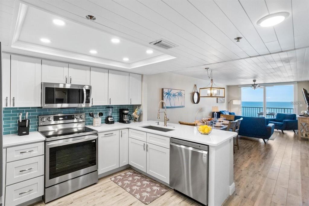 A modern kitchen with white cabinets, stainless steel appliances, and a view of the ocean — 20000 GULF BOULEVARD UNIT 707, INDIAN SHORES, FL