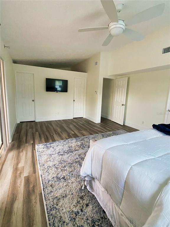 A bedroom with a vaulted ceiling, wood-look flooring, a large area rug, and pool access — 2400 LAUDERDALE COURT, ORLANDO, FL