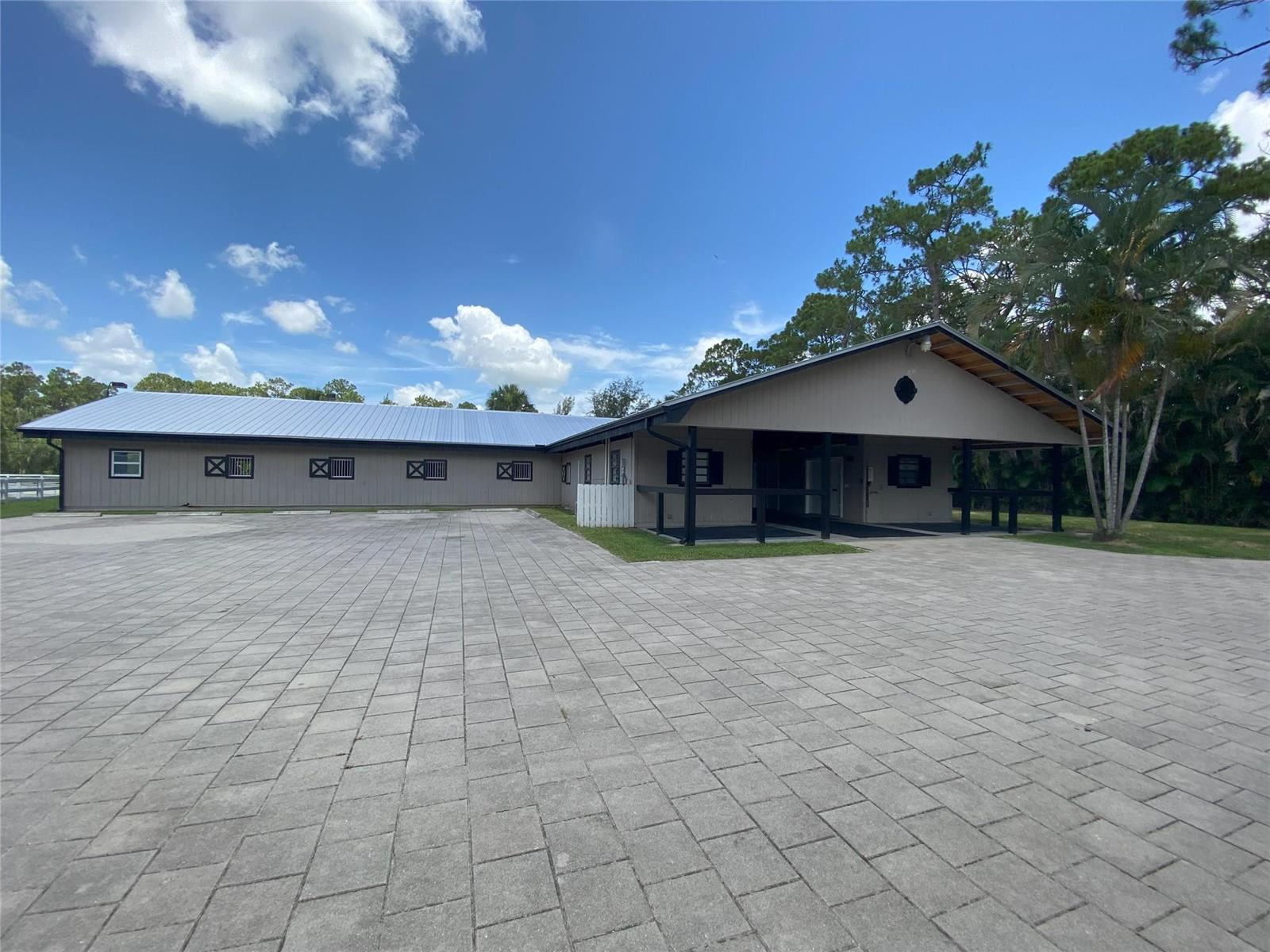 A single-story building with a metal roof and paved parking lot under a blue sky — 2315 Deer Run Boulevard, Loxahatchee FL 33470, LOXAHATCHEE, FL