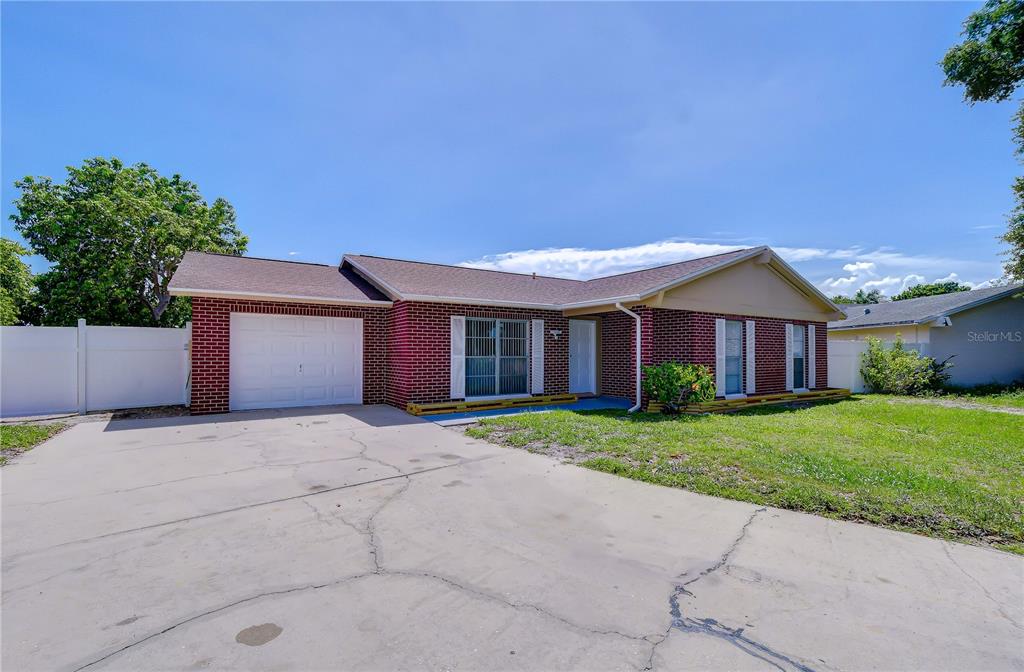 A single-story brick house features a white garage door and a concrete driveway — 7214 NIA LANE, TAMPA, FL