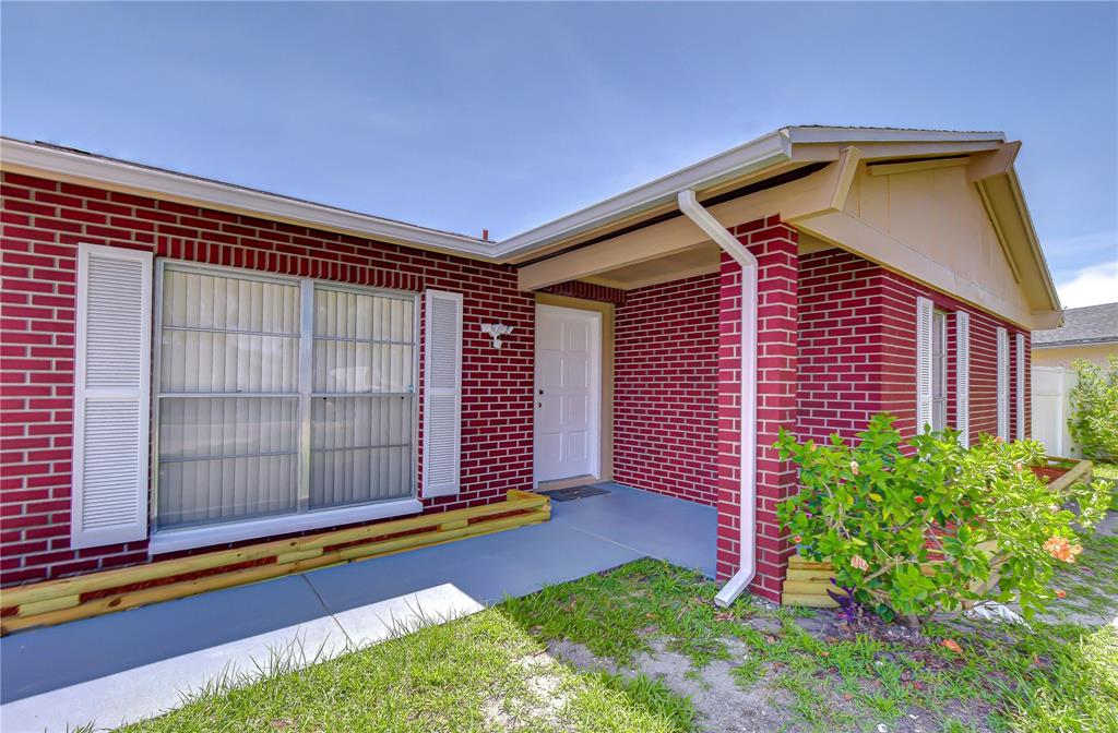 The exterior of a red brick house features a white front door and window shutters — 7214 NIA LANE, TAMPA, FL