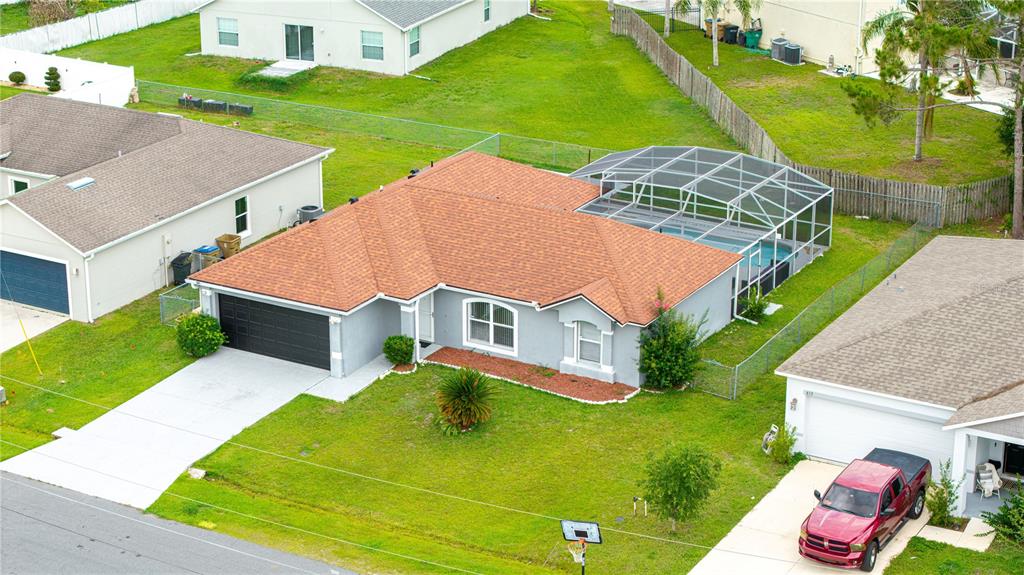 An aerial view of a single-story suburban house with a screened pool and garage — 611 JURA LANE, KISSIMMEE, FL