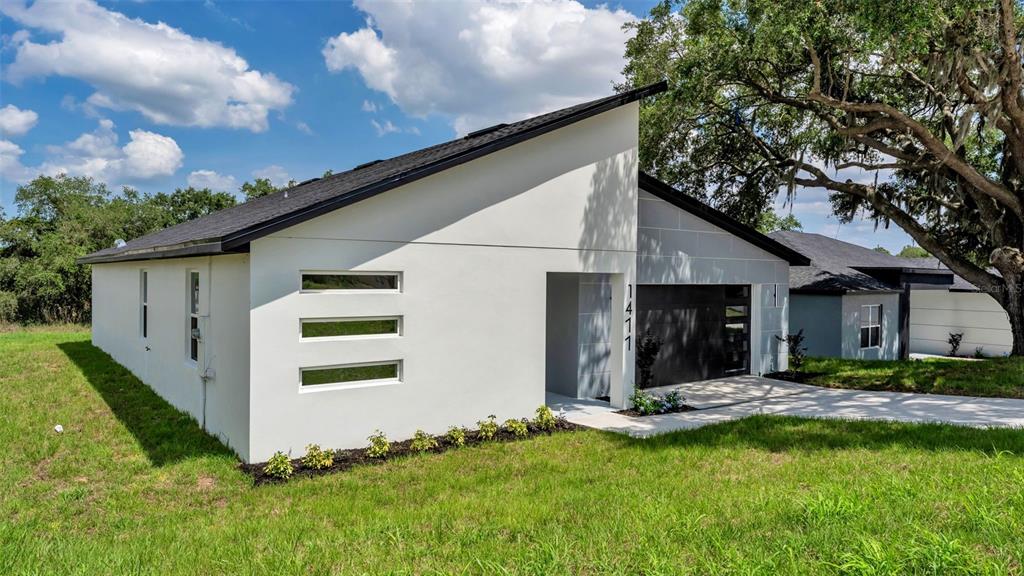 A modern white house with a sloped roof, horizontal windows, and a dark garage door — 1477 HOLLY HILL ROAD, DAVENPORT, FL