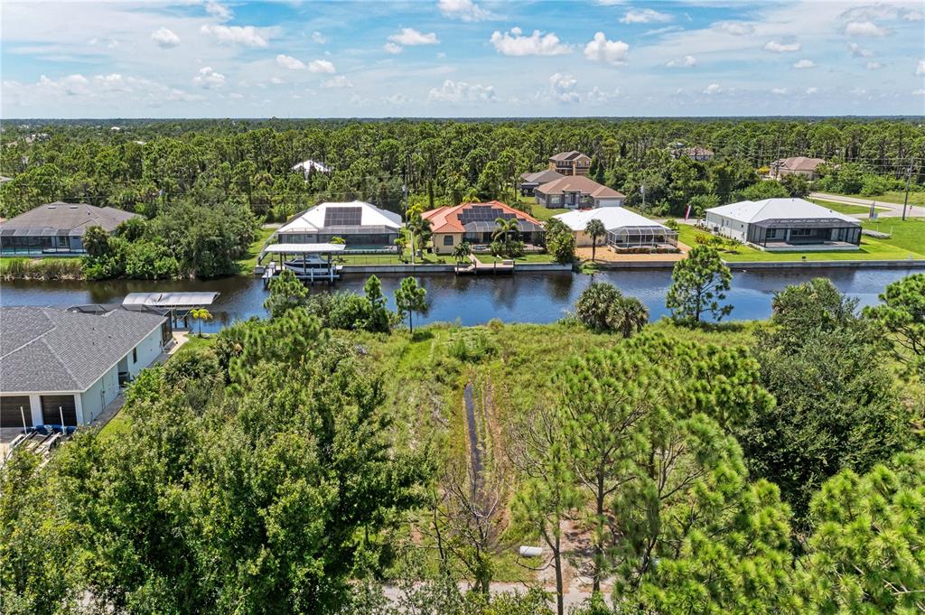 An aerial view shows a canal-front lot with surrounding houses and dense vegetation — 8185 DAFOE STREET, PORT CHARLOTTE, FL