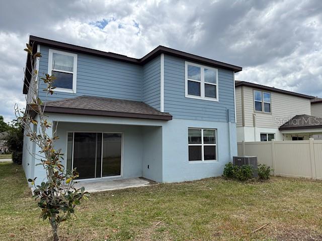 The exterior of a two-story house features blue siding, a covered patio, and a fenced yard — 30169 SKYLARK DRIVE, WESLEY CHAPEL, FL