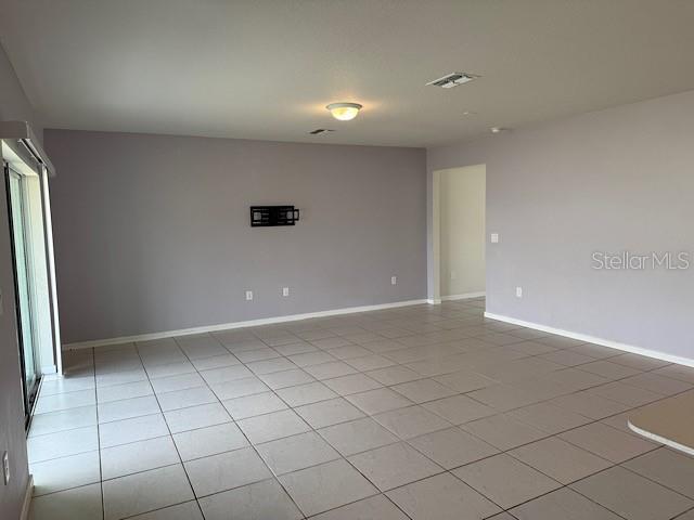 An empty living room features light-colored tile flooring, pale walls, and a sliding glass door — 30169 SKYLARK DRIVE, WESLEY CHAPEL, FL