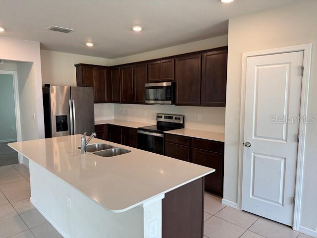 A kitchen features dark wood cabinets, stainless steel appliances, and a large white island — 30169 SKYLARK DRIVE, WESLEY CHAPEL, FL