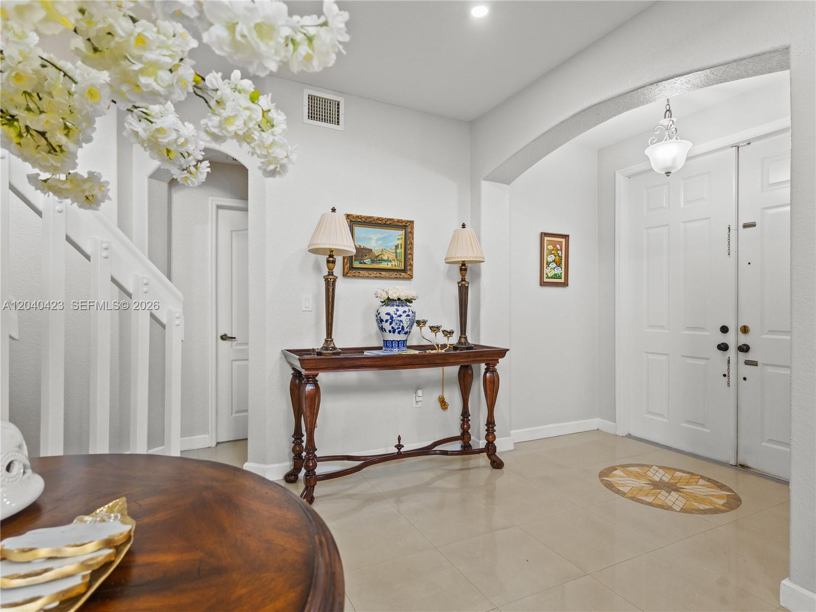 An entryway features a console table, two lamps, a staircase, and a double front door — 8542 NW 111th Ct, Doral FL 33178, DORAL, FL