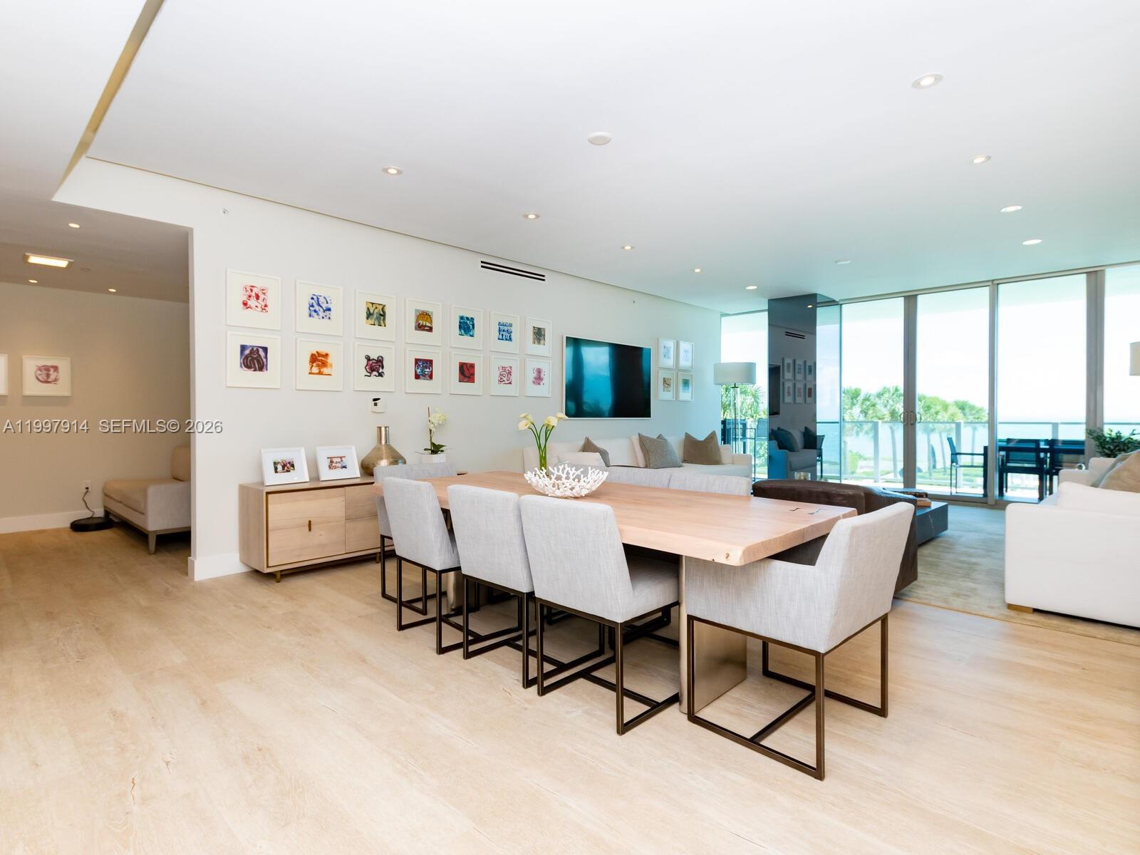 A dining area features a light wood table, upholstered chairs, and a gallery wall — 360 Ocean Dr # 304S, Key Biscayne FL 33149, KEY BISCAYNE, FL