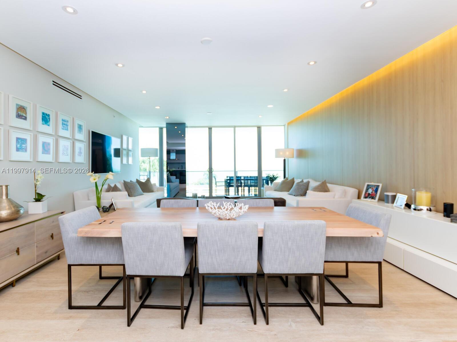 A dining room features a large wooden table with grey chairs and light wood flooring — 360 Ocean Dr # 304S, Key Biscayne FL 33149, KEY BISCAYNE, FL