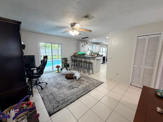 A room with tile flooring, a large area rug, a ceiling fan, and kitchen access — 706 VENTERS STREET, PORT ORANGE, FL
