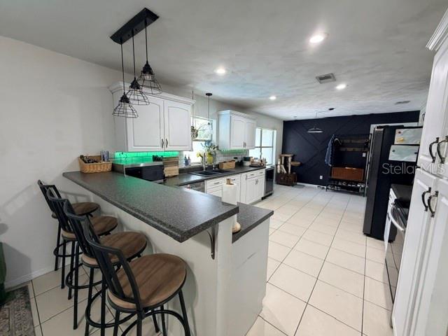 A kitchen features white cabinets, a dark countertop breakfast bar, and three pendant lights — 706 VENTERS STREET, PORT ORANGE, FL