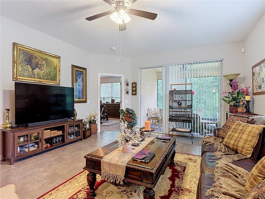 A living room features tile floors, a ceiling fan, a television console, and a birdcage — 700 SHADY CANYON WAY, POINCIANA, FL