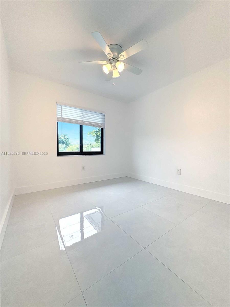 A bright, empty bedroom features white walls, light-colored tile flooring, and a ceiling fan — 3079 NW 11th St # 3053, Miami FL 33125, MIAMI, FL