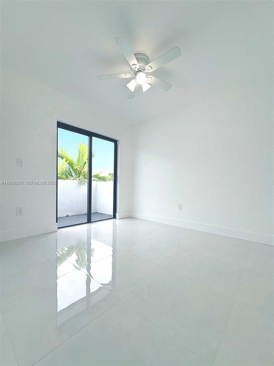 A bright, empty room features white walls, glossy tile flooring, and a sliding glass door — 3079 NW 11th St # 3053, Miami FL 33125, MIAMI, FL