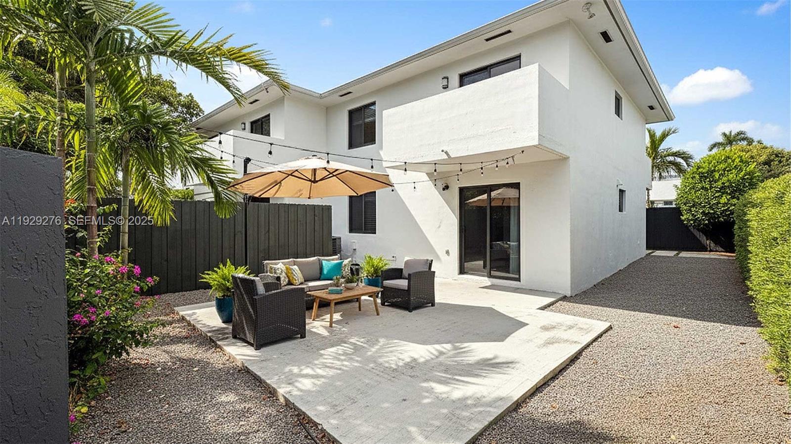 A white two-story house features a concrete patio with outdoor furniture and string lights — 3079 NW 11th St # 3053, Miami FL 33125, MIAMI, FL