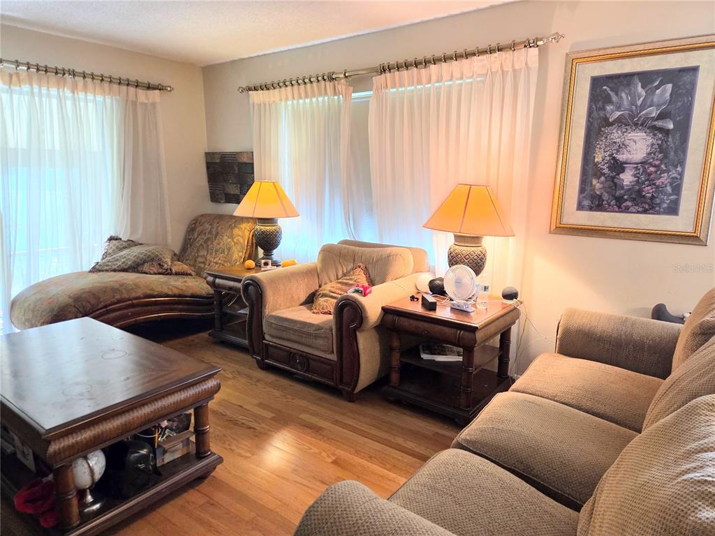 A living room features a fireplace, beige sofa, chaise lounge, and sliding glass balcony doors — 2367 FLANDERS WAY UNIT D, SAFETY HARBOR, FL