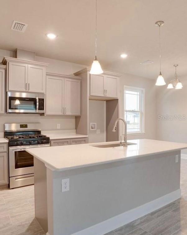 A kitchen with light gray cabinets, stainless steel appliances, and a white quartz island countertop — 24339 SW 18TH LANE, NEWBERRY, FL