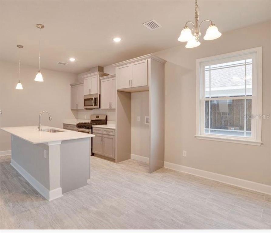 A kitchen with light gray cabinets, a white island, and tile flooring in an open space — 24339 SW 18TH LANE, NEWBERRY, FL