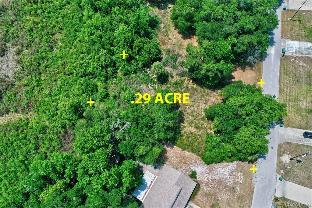 An aerial view shows a wooded, rectangular lot with yellow markers indicating its boundaries — 9390 E MISTWOOD DRIVE, INVERNESS, FL