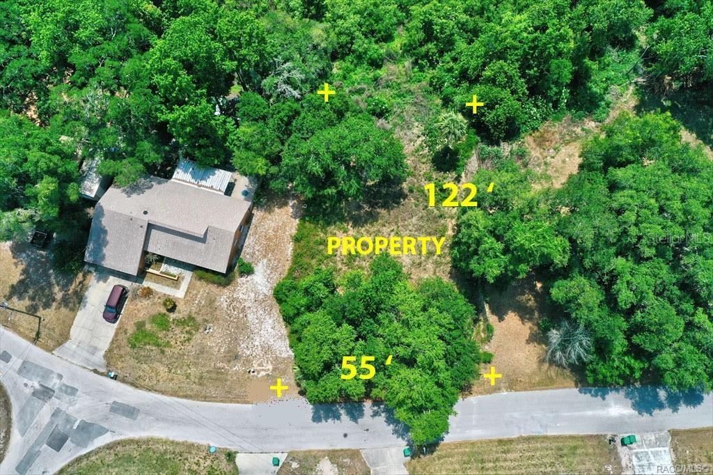 An aerial view shows a vacant, wooded lot next to a house with a driveway — 9390 E MISTWOOD DRIVE, INVERNESS, FL