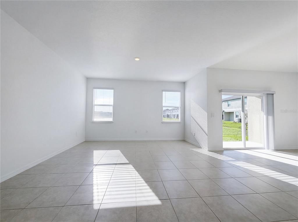 An empty room with white walls, tile flooring, two windows, and a sliding glass door — 9443 GULF SHORE TERRACE, PARRISH, FL