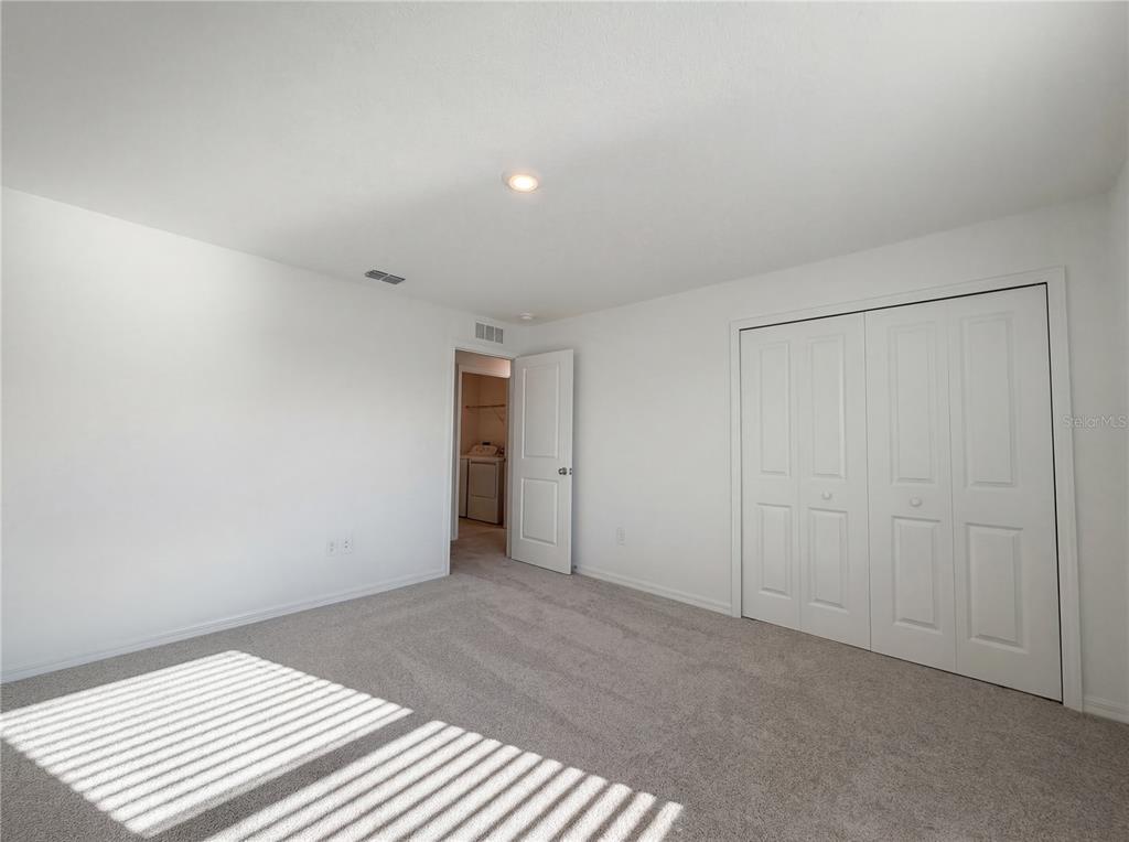 A bedroom with white walls, gray carpet, a closet with double doors, and an open doorway — 9443 GULF SHORE TERRACE, PARRISH, FL